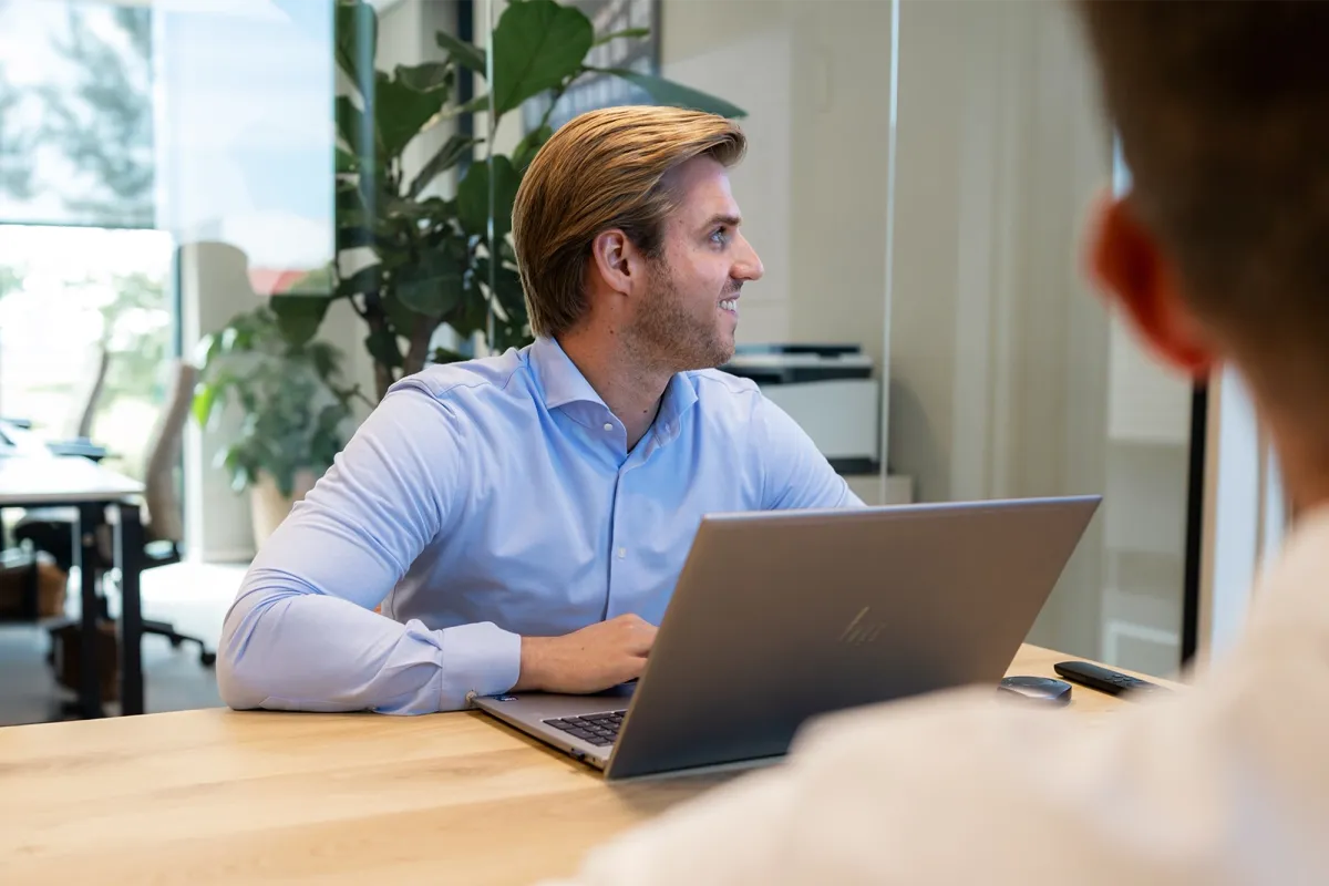 Teamlid van Fynem in gesprek aan tafel achter een laptop