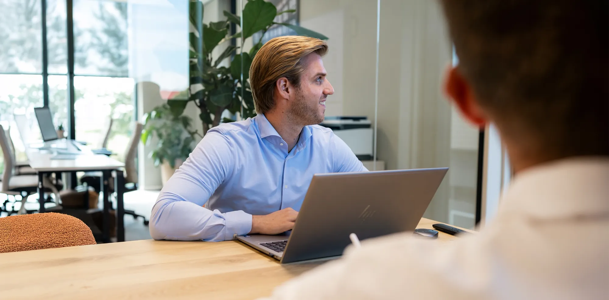 Gesprek aan tafel Teamlid van Fynem in gesprek aan tafel achter een laptop